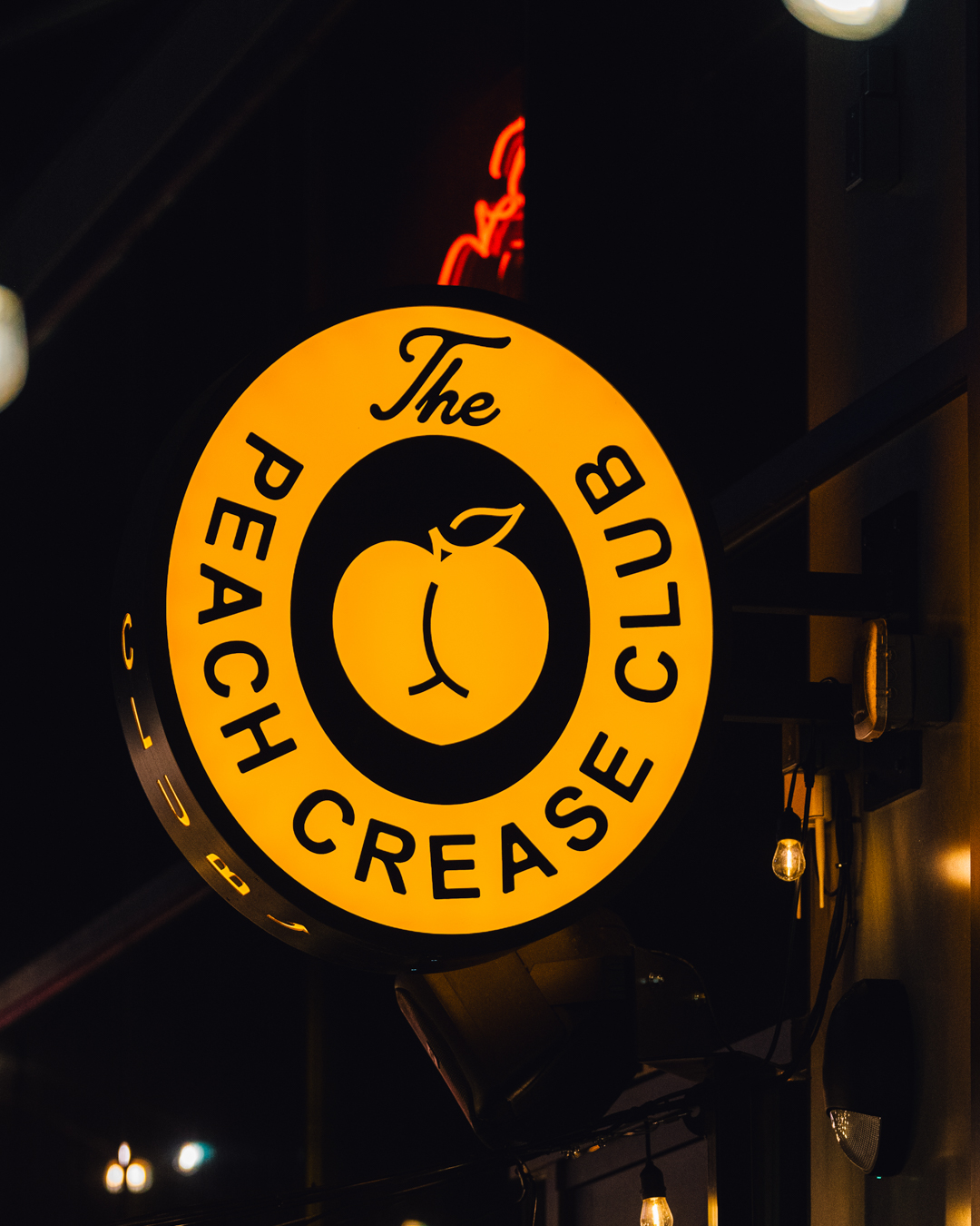 custom illuminated bar sign for Peach Crease Club attracting foot traffic at night Denver