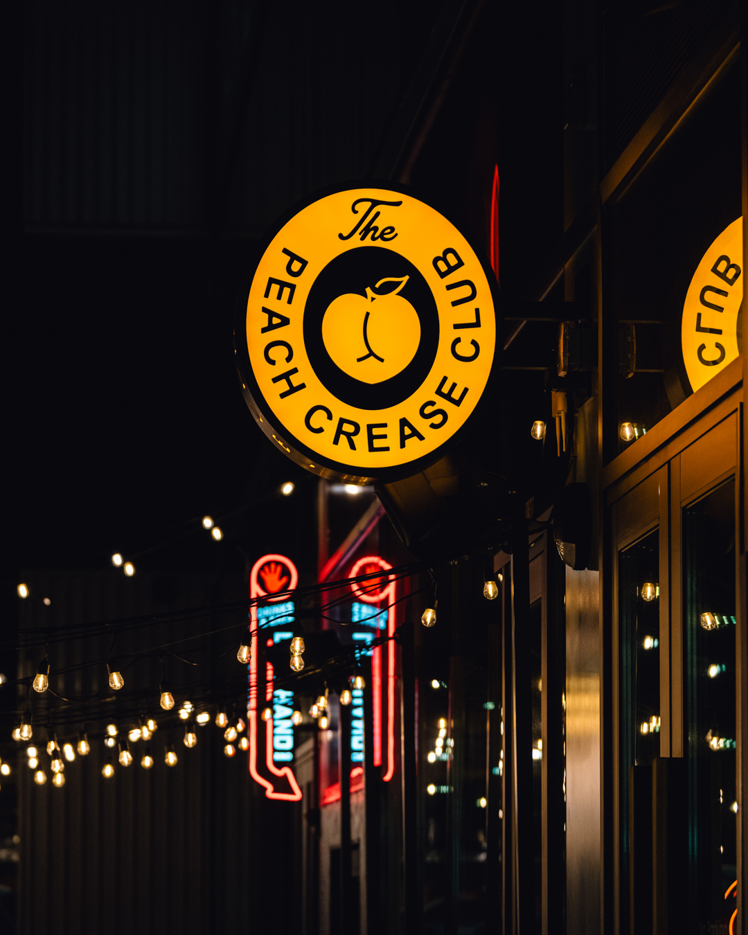 nighttime detail of Peach Crease Club custom sign fabrication and glow effect in RiNo Denver