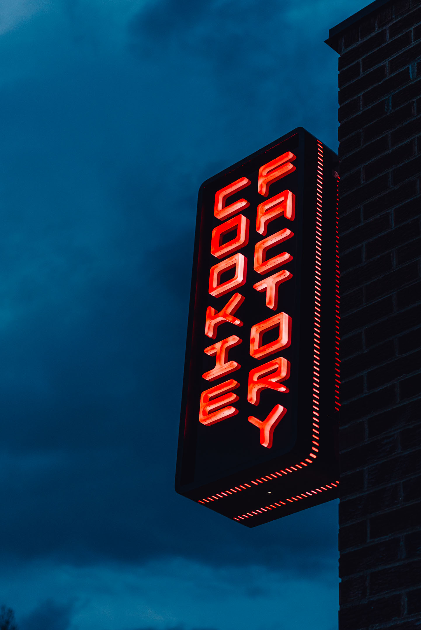 Close-up view of illuminated push-through letters on custom Cookie Factory blade sign.