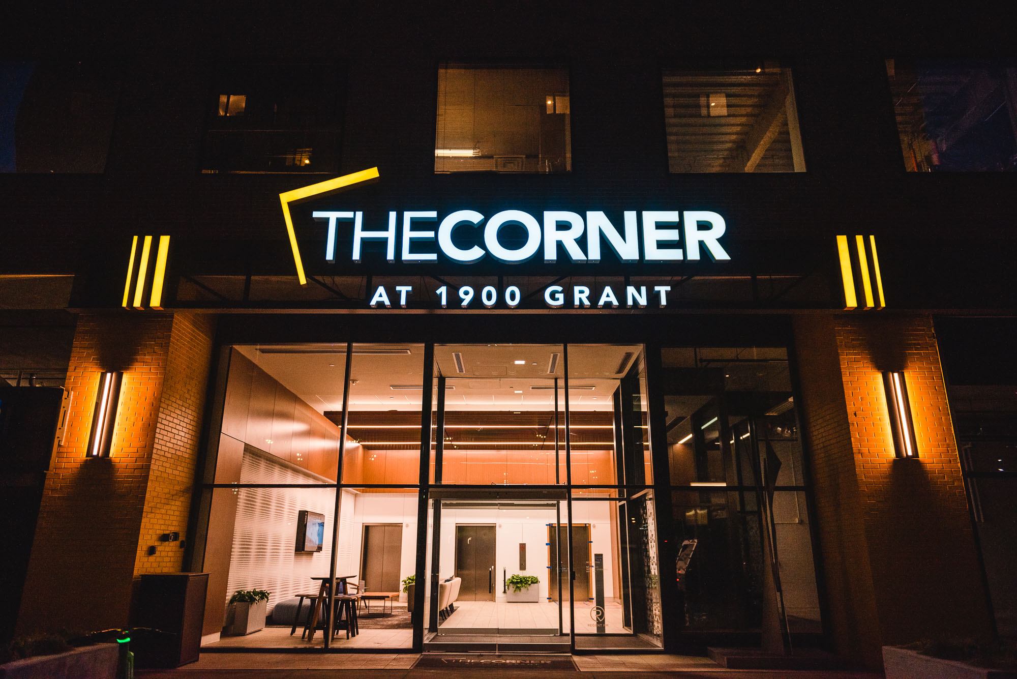 Illuminated multifamily signage and architectural lighting installed above the entrance at The Corner at 1900 Grant.