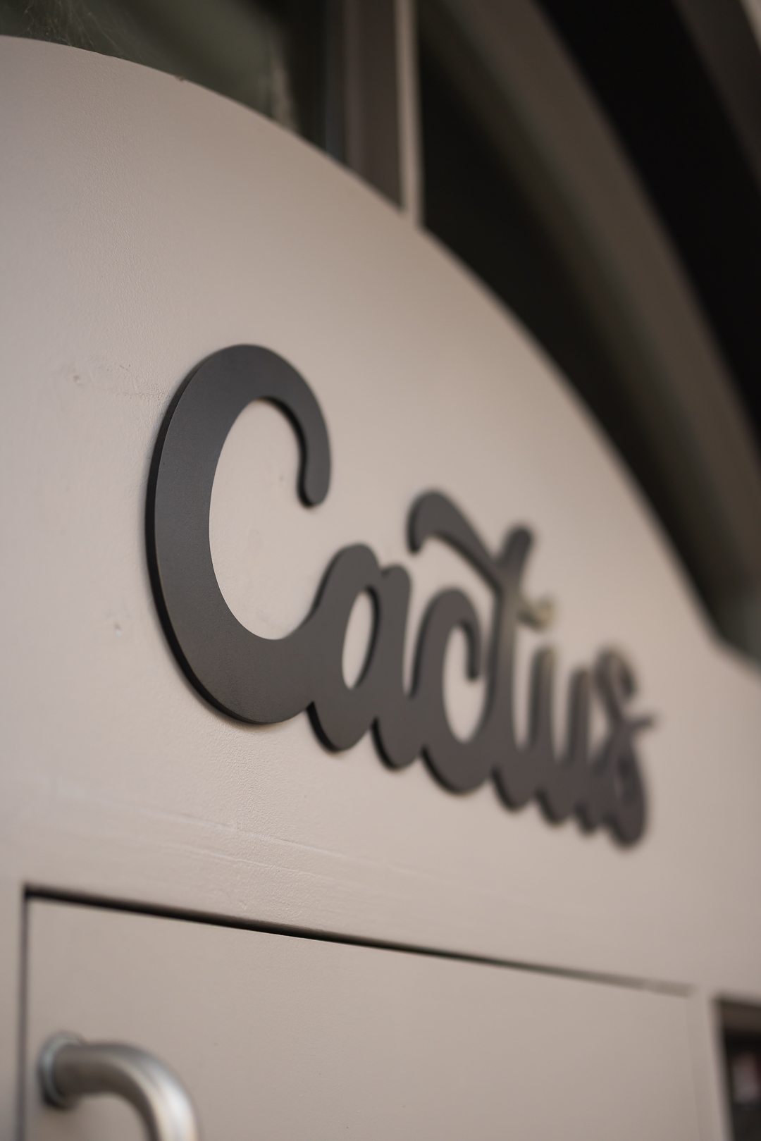 Close-up of dimensional black aluminum Cactus logo lettering mounted to the building entrance