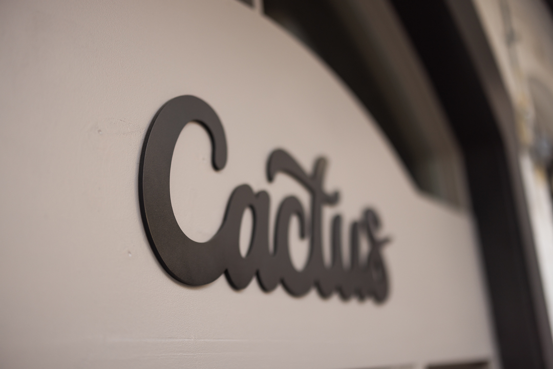 Angled close-up of the custom Cactus logo sign showing the dimensional aluminum construction